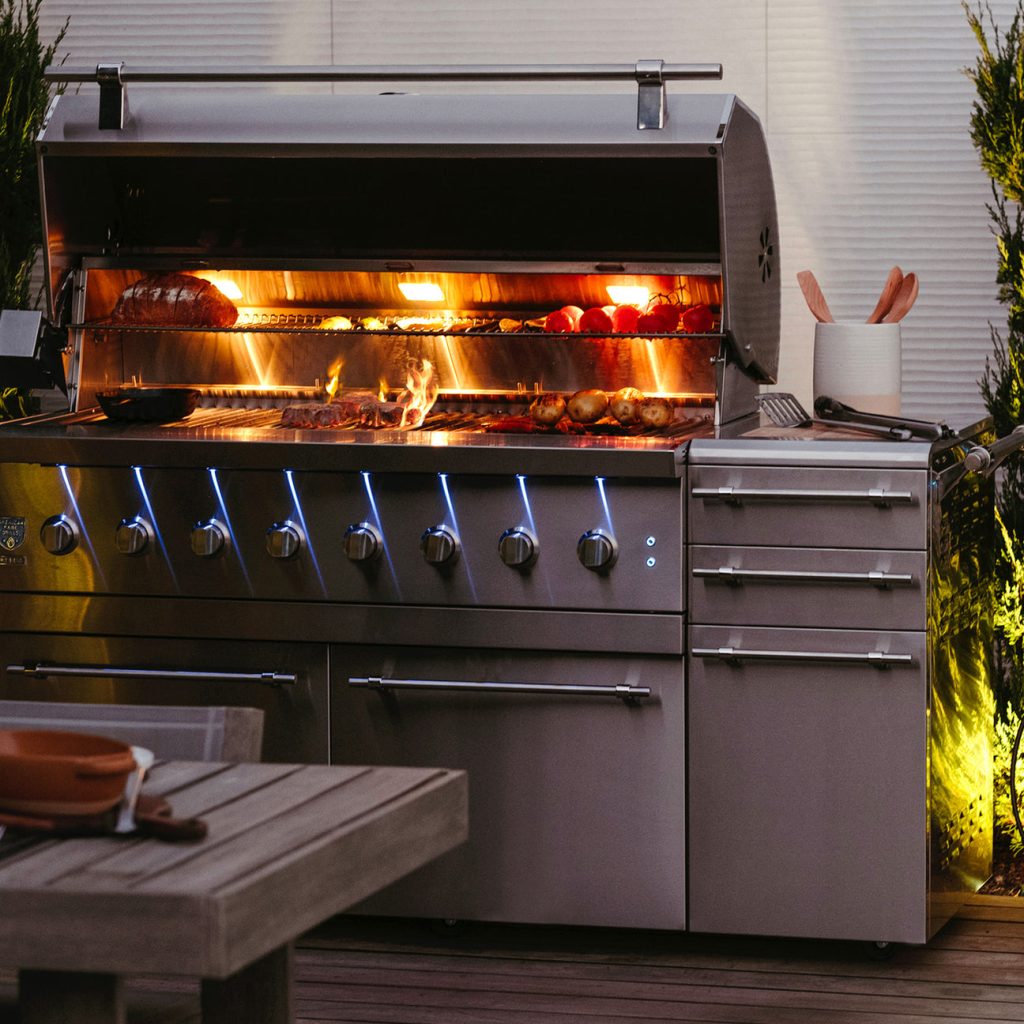American Made Grills hybrid grill with open flames on an outdoor patio