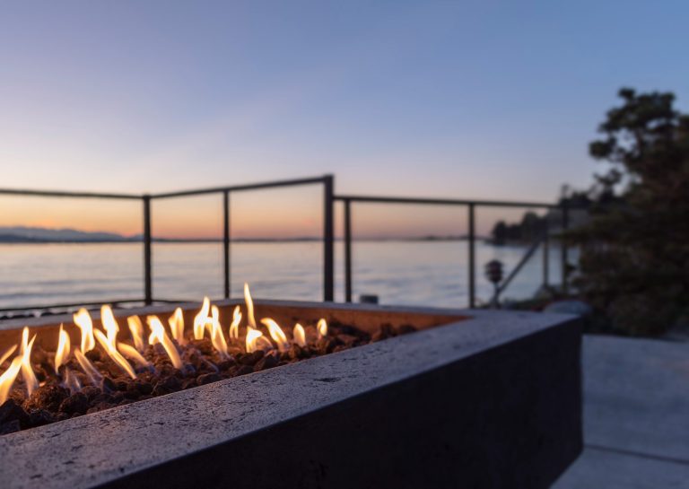 Backyard gas fire pit at sunset by the water