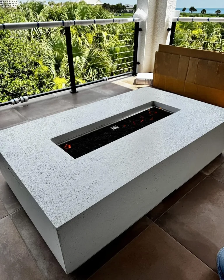 Rectangular white concrete fire table on a balcony with a water view
