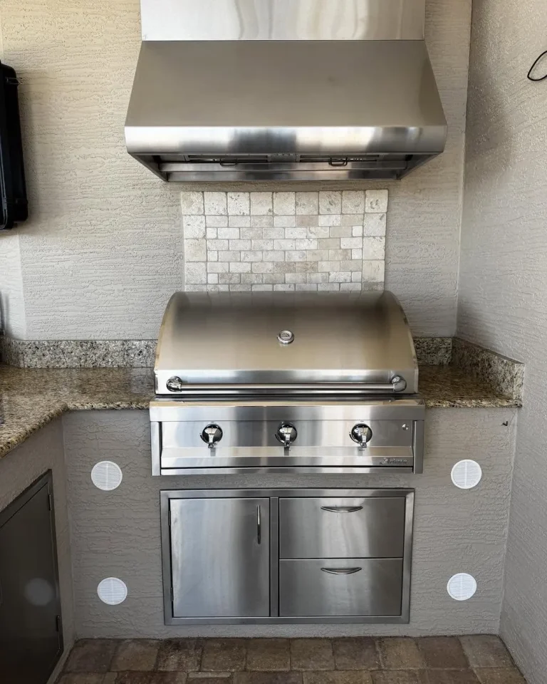 Artisan 36 inch built-in grill under a vent hood in an outdoor kitchen