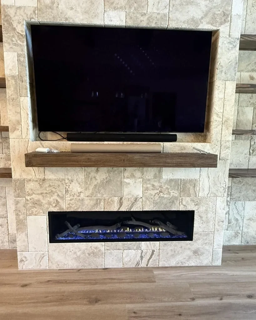 Linear gas fireplace with blue glass in a stone feature wall under a TV