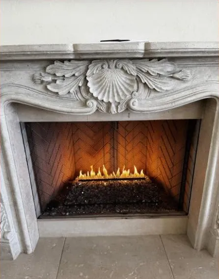 Vent-free gas log set burning in a carved stone fireplace surround