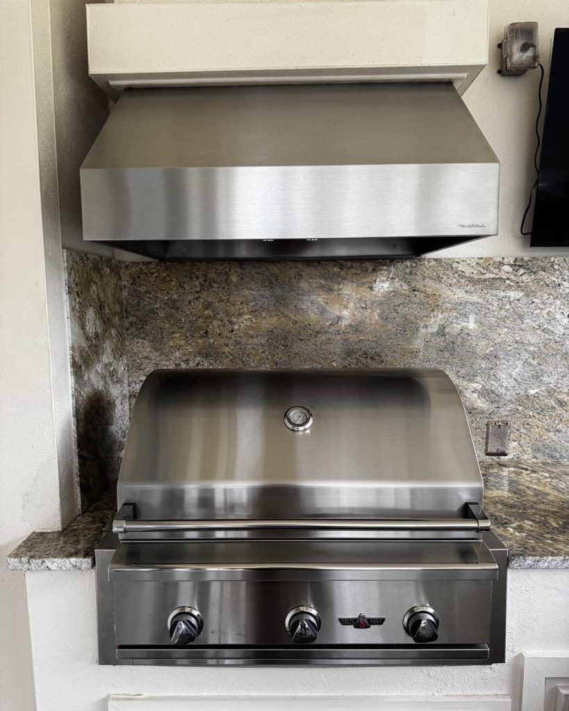 New stainless outdoor vent hood above a built-in grill in a Palm Coast area summer kitchen